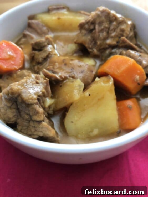 A close-up view of a rich beef stew bubbling in a slow cooker, thick and hearty, almost ready to serve.