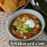 21 Delicious Makeovers for Your Leftover Shredded Chicken 16 A steaming bowl of chicken tortilla soup, garnished with diced avocado and a dollop of sour cream.