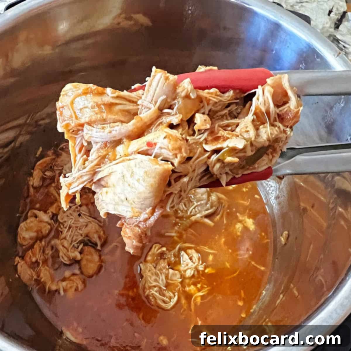 21 Delicious Makeovers for Your Leftover Shredded Chicken 4 Salsa chicken being gently lifted with tongs from an Instant Pot, showcasing its readiness for shredding.