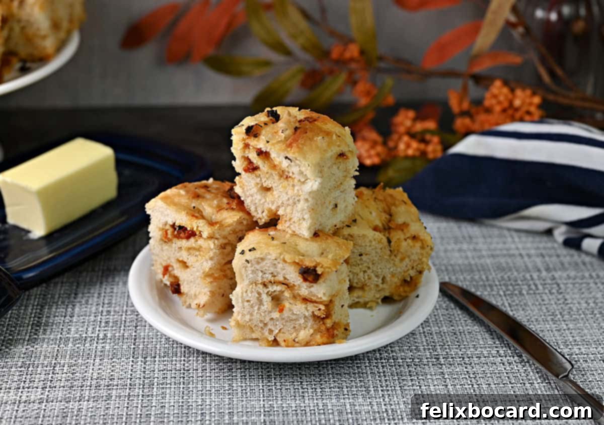 Simple Sun-Dried Tomato & Rosemary Focaccia 2 Stacked pieces of golden-brown sun-dried tomato focaccia bread on a small plate, ready to be served.