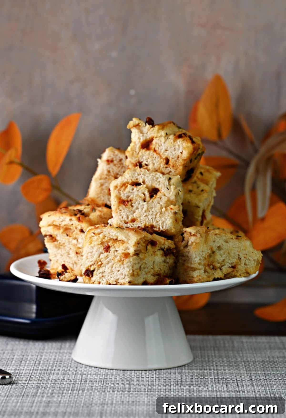 Simple Sun-Dried Tomato & Rosemary Focaccia 11 A charming stack of smaller-batch sun-dried tomato focaccia squares presented on a footed serving plate.