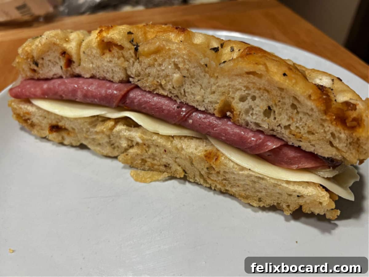 Simple Sun-Dried Tomato & Rosemary Focaccia 13 A gourmet sandwich made using a thick slice of focaccia bread, filled with salami, cheese, and greens.