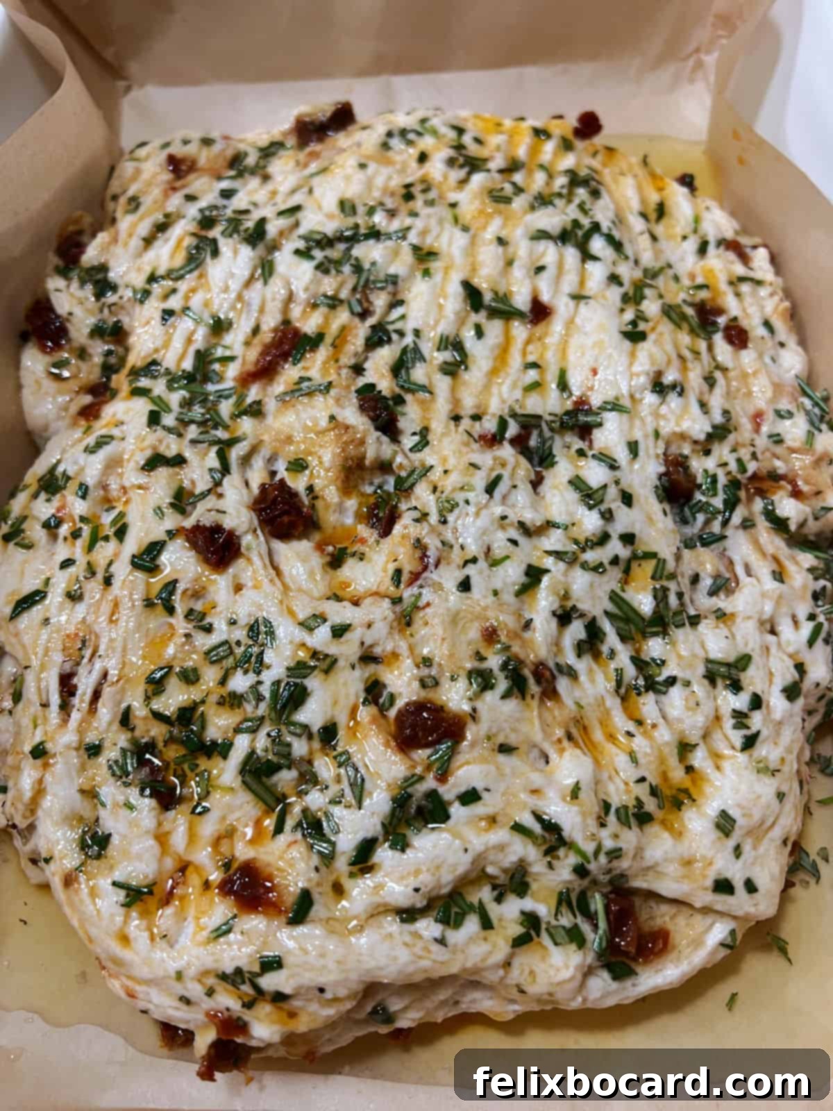 Simple Sun-Dried Tomato & Rosemary Focaccia 8 Shaped focaccia dough in a parchment-lined baking pan, generously sprinkled with fresh rosemary and flaky sea salt, ready for its final proof.