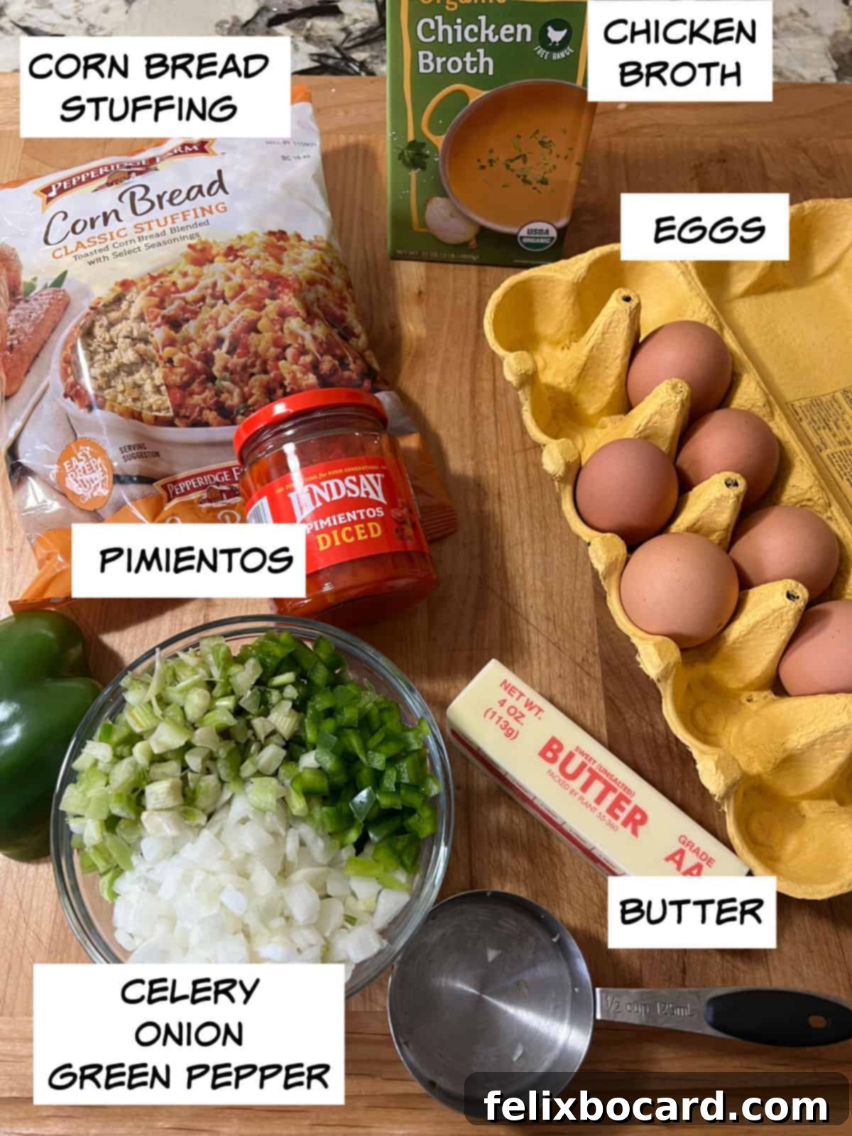 Arrangement of ingredients for cornbread dressing: cornbread stuffing mix, chicken broth, fresh eggs, butter, green bell pepper, celery, onion, and pimientos.