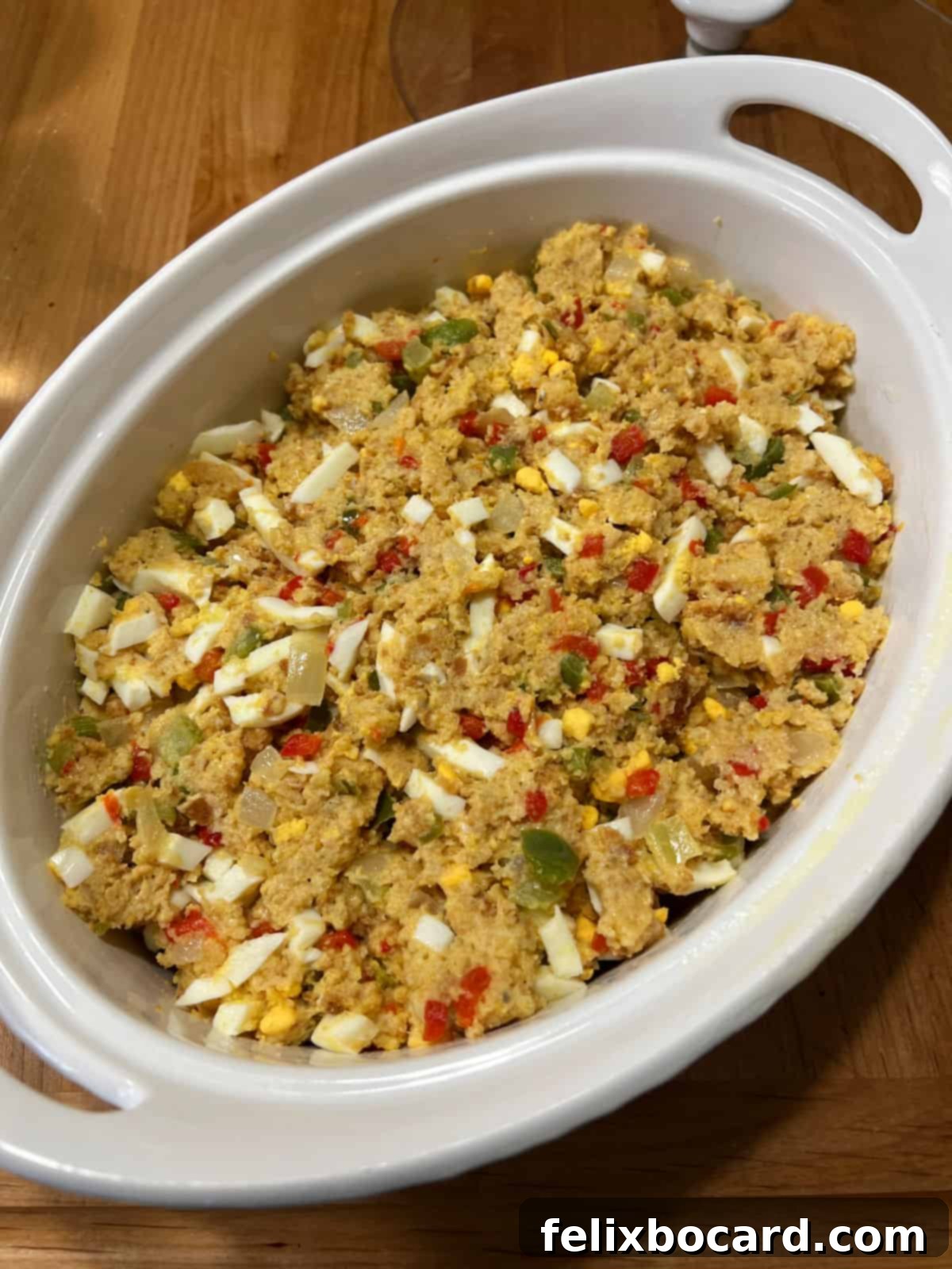 The cornbread dressing mixture has been transferred neatly into an oval casserole dish, ready for baking.