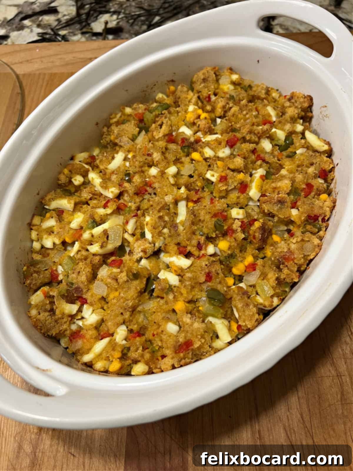 A golden-brown, fully cooked cornbread dressing, with visible chopped hard-boiled eggs throughout, fresh out of the oven.