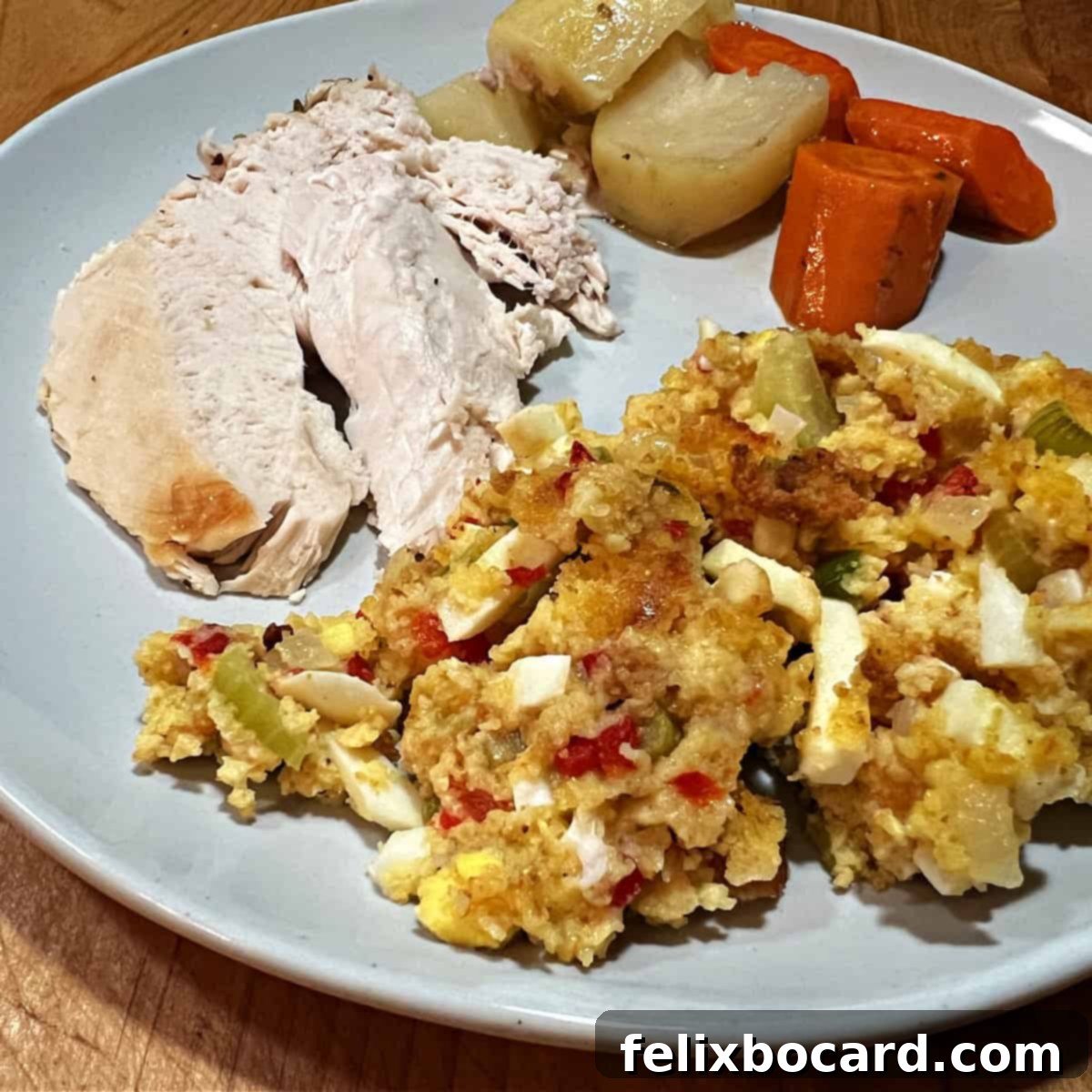 A beautifully composed plate featuring cornbread dressing with hard-boiled eggs, served alongside slices of roasted turkey and green beans, showcasing a complete holiday meal.