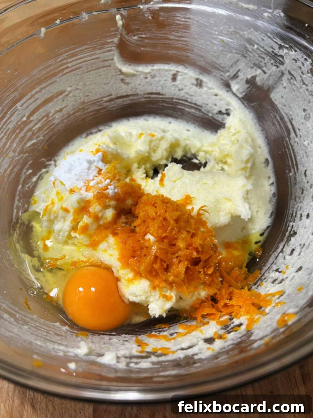 Adding orange zest and egg to the bowl.