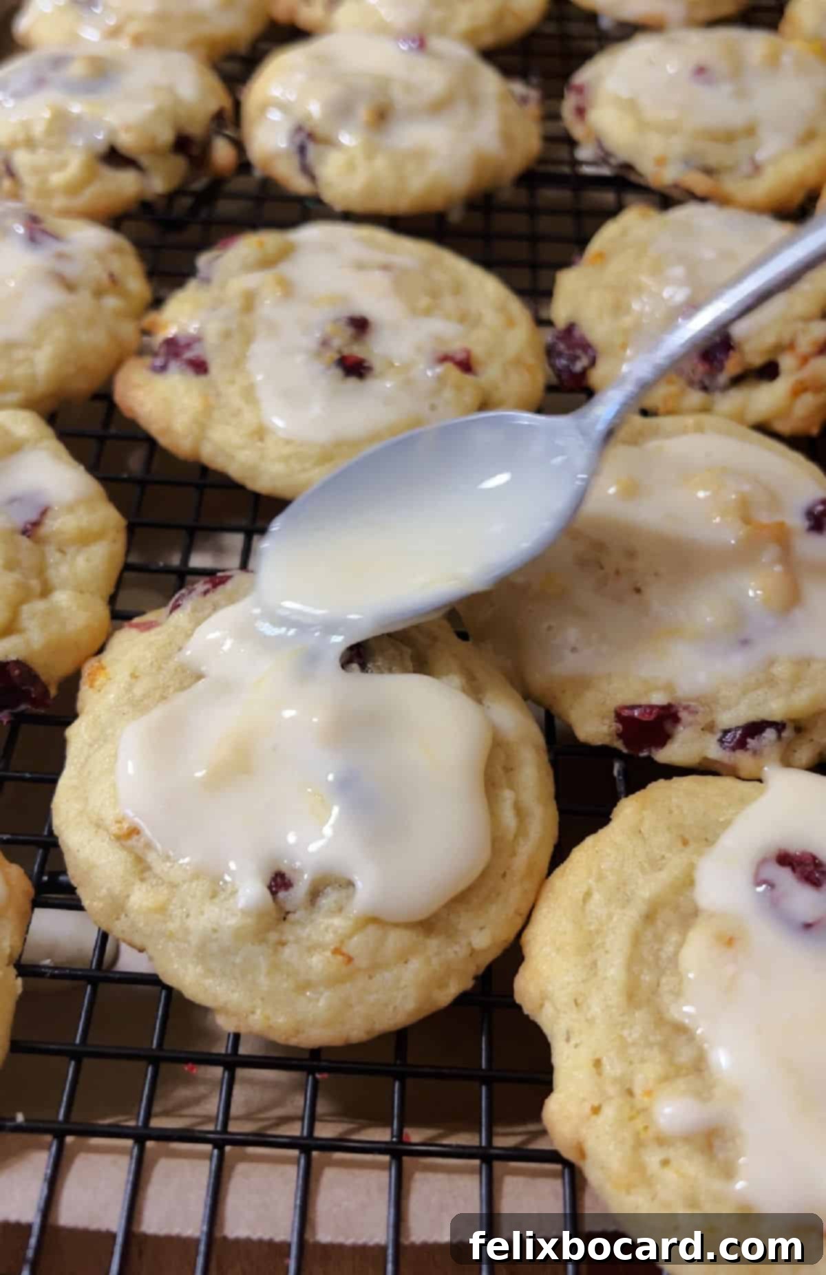 A small spoon drizzling eh glaze on the cookies.