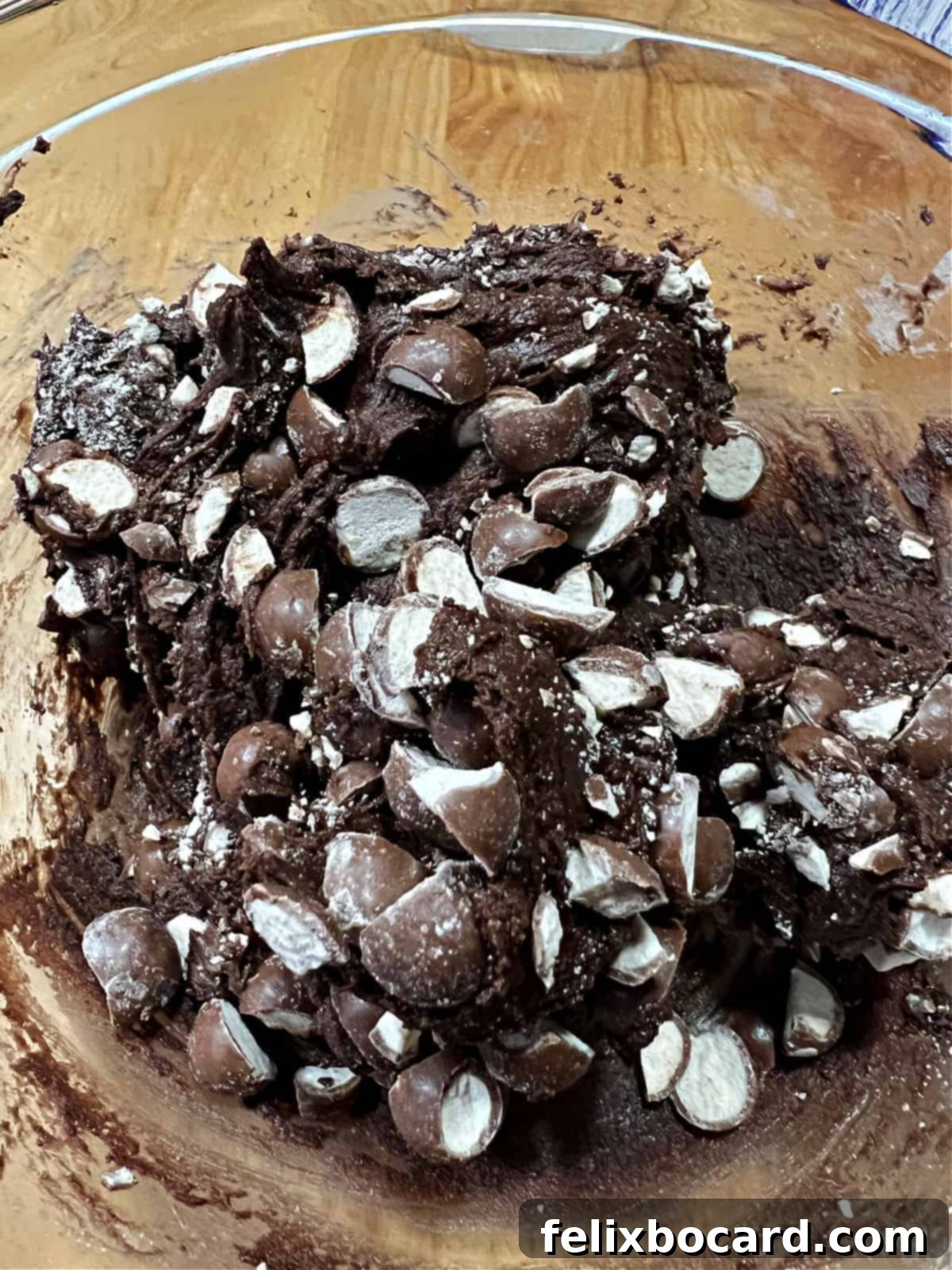 Adding chopped malted milk balls to the chocolate cookie dough.