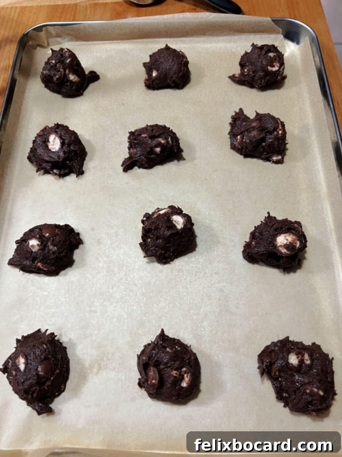 Portions of cookie dough on a baking sheet.