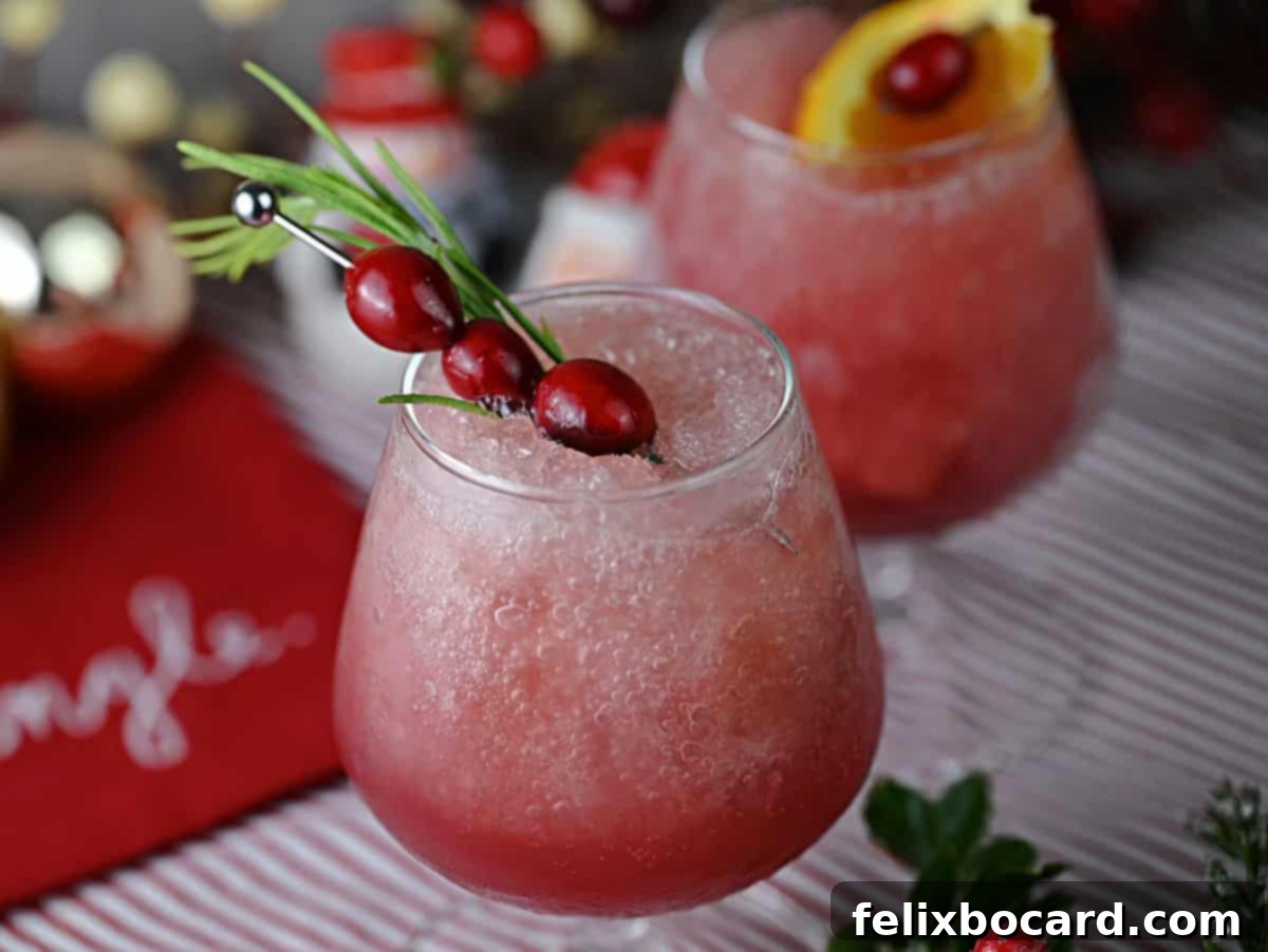 Top down view of a frozen cranberry rum slush garnished with fresh cranberries and a rosemary sprig.