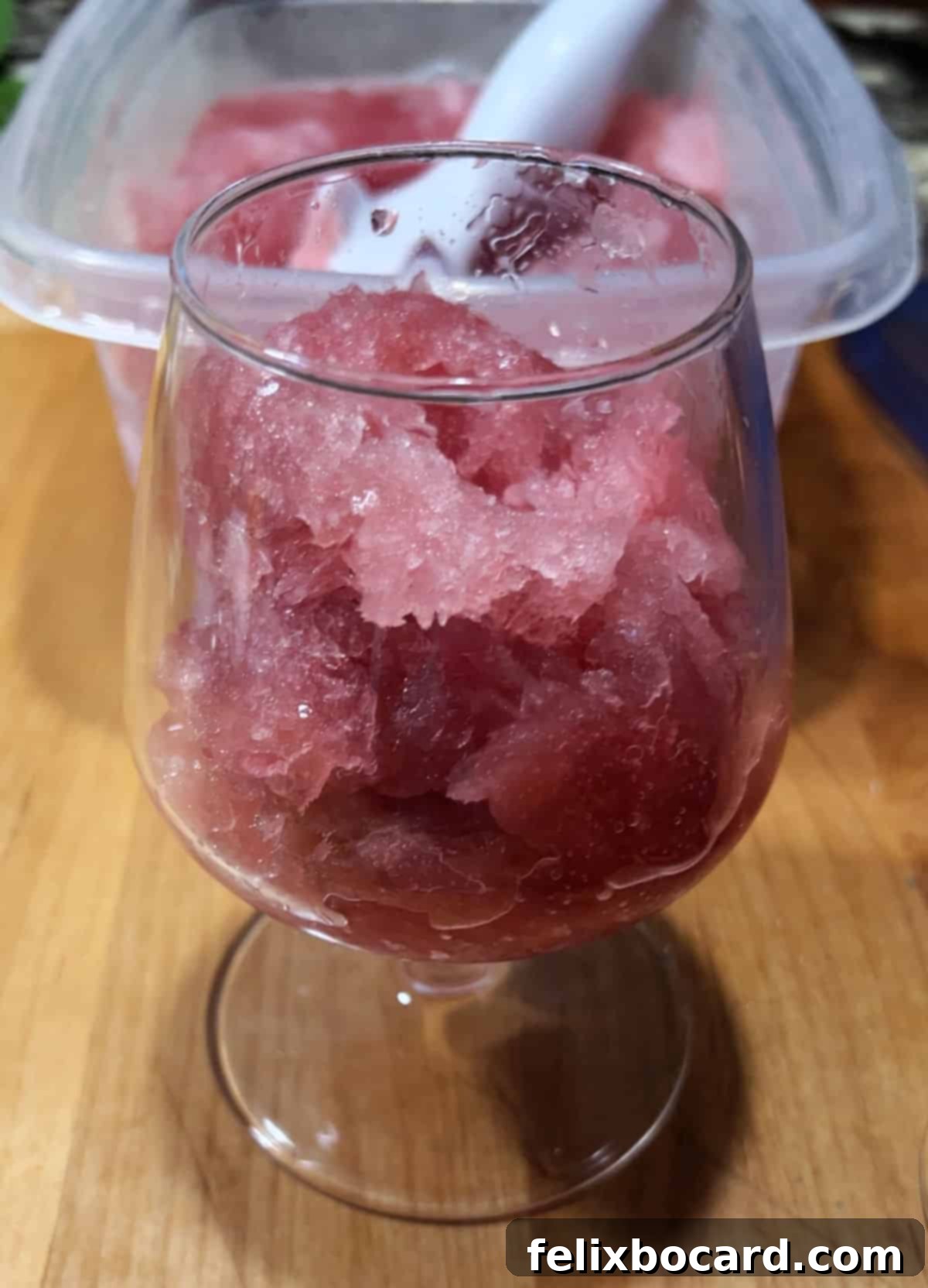 Slushee cranberry rum mix scooped to half fill a glass.