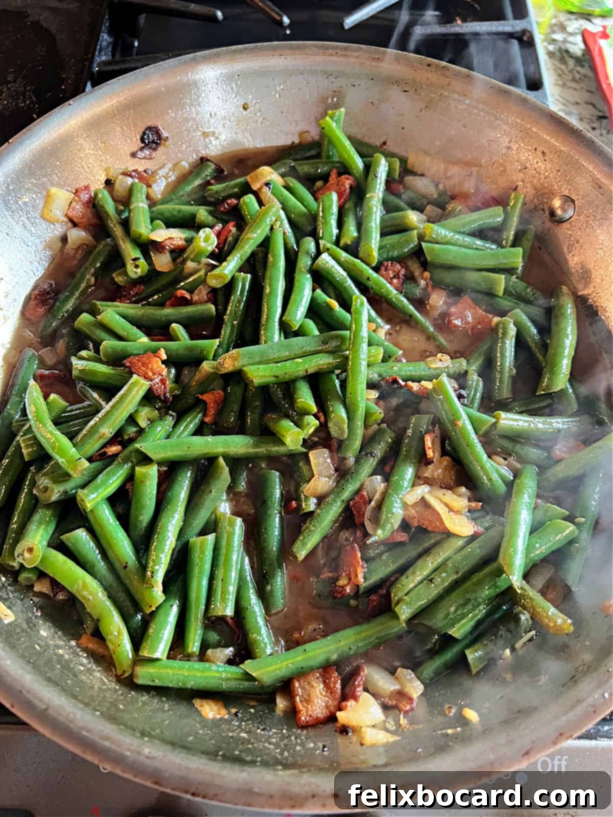 Cooked green beans in a skillet with the liquid significantly reduced, concentrating the flavors.