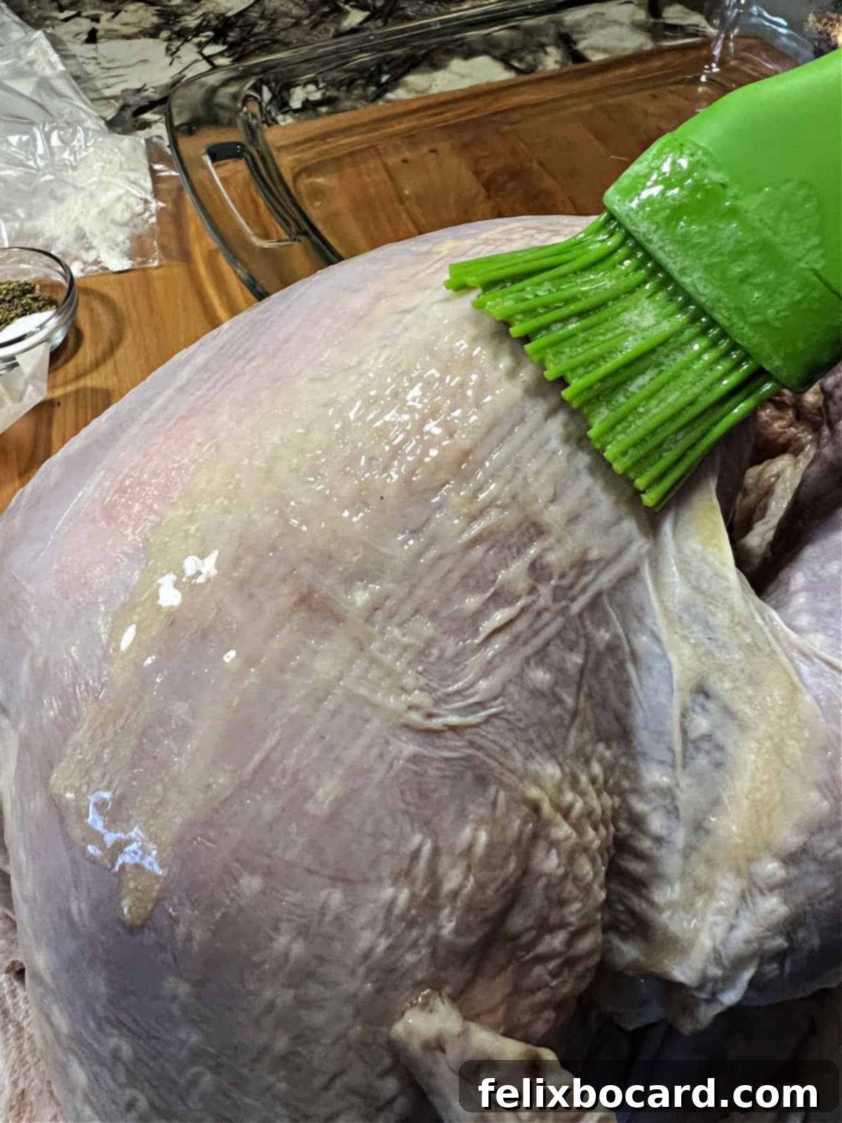 Brushing melted butter over the turkey's surface.