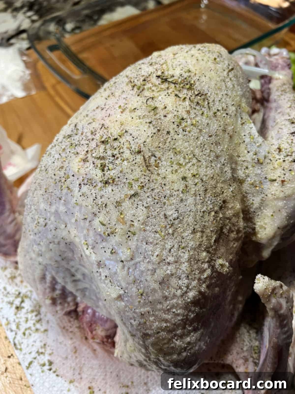 Seasonings sprinkled all over the surface of the buttered bird.