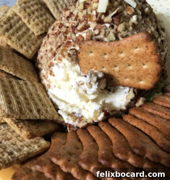 Football shaped cheese ball on a serving platter surrounded by various crackers.