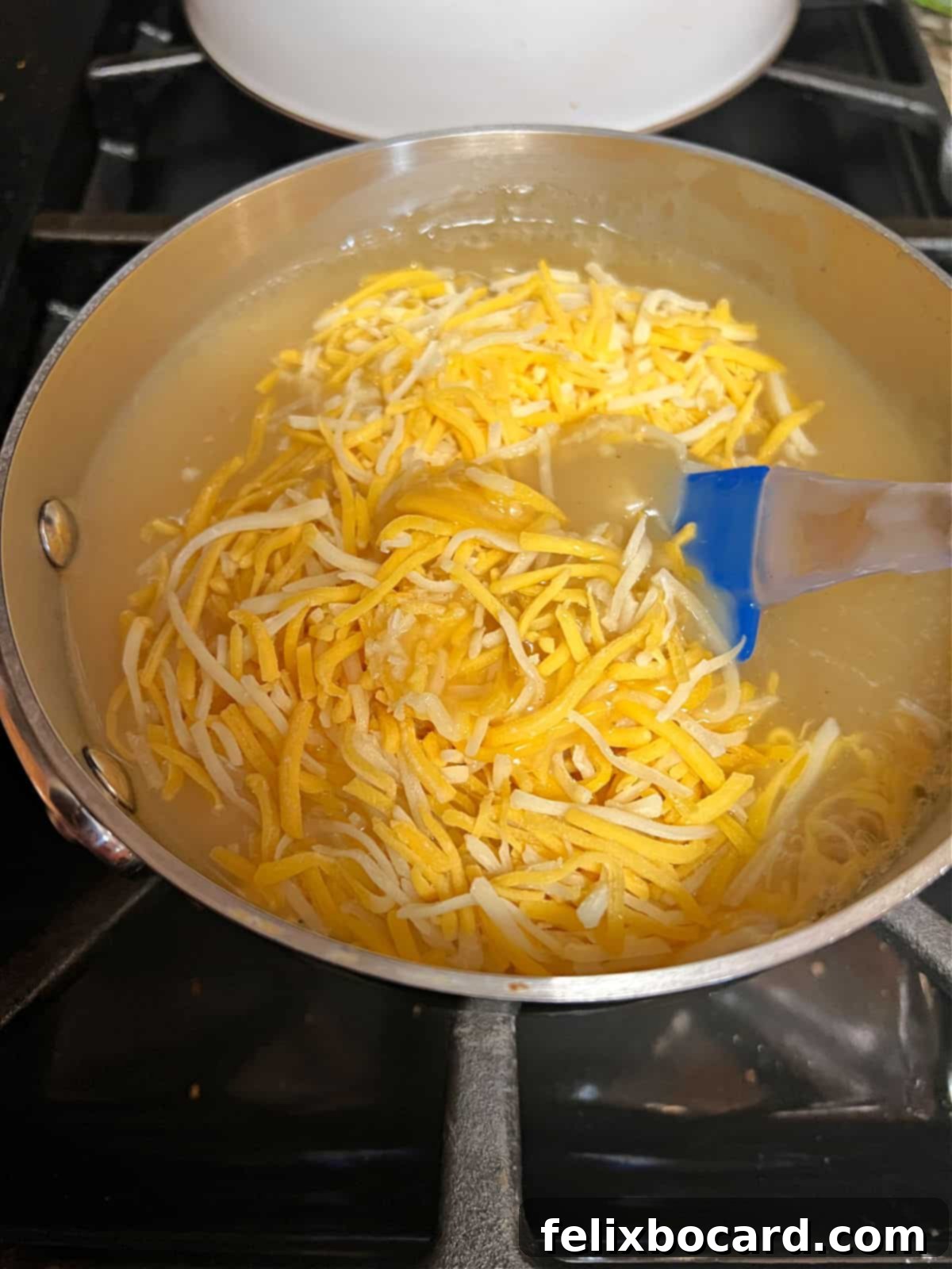 Shredded Cheddar Jack cheese being stirred into warm, simmering turkey gravy in a saucepan on a stovetop, creating a richer, thicker sauce.