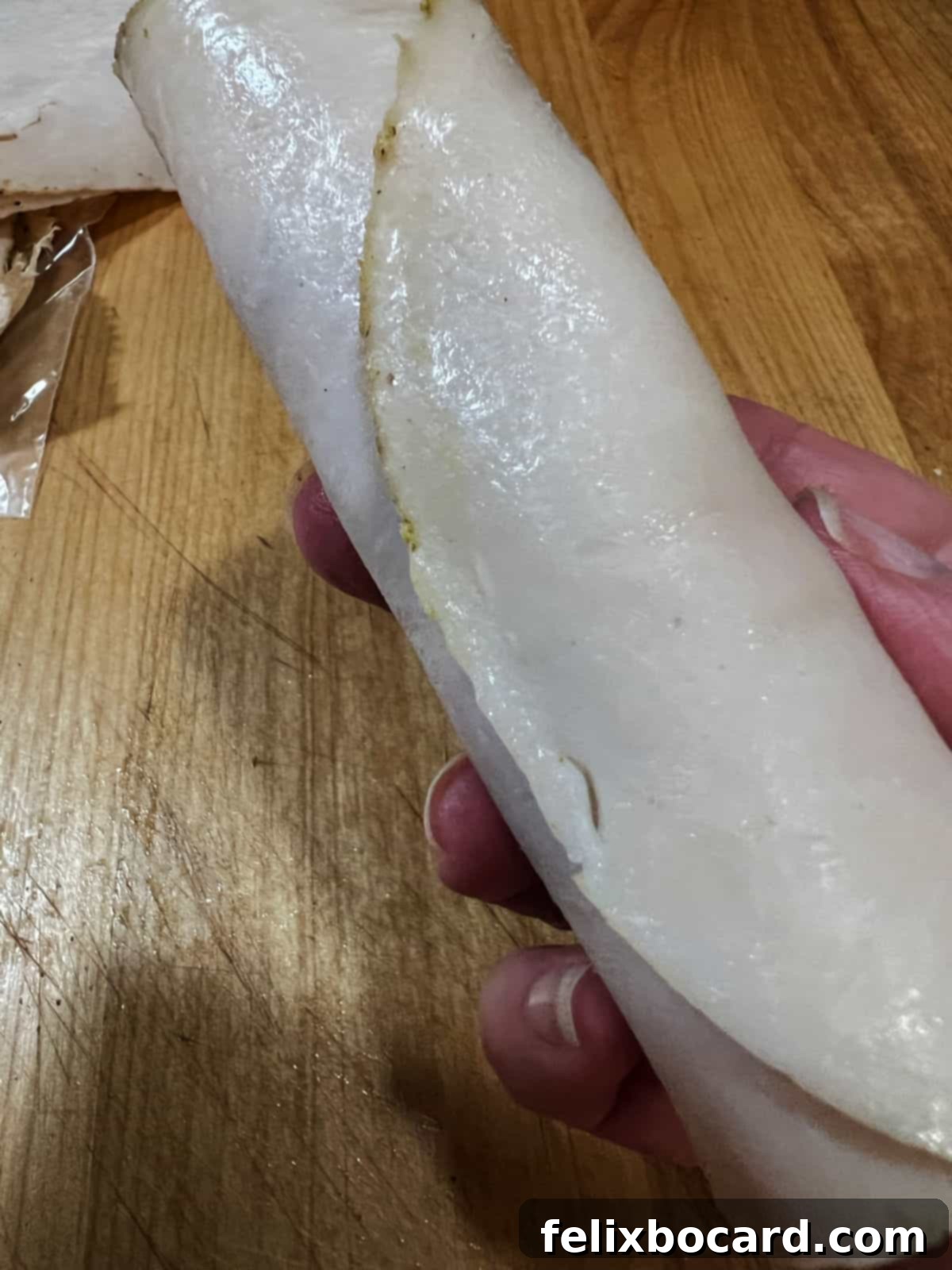 A perfectly rolled turkey slice, filled with savory stuffing, resting on a flat surface, ready for baking.