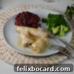 Turkey and stuffing roll up cut open on a plate and served with cranberry sauce and broccoli.