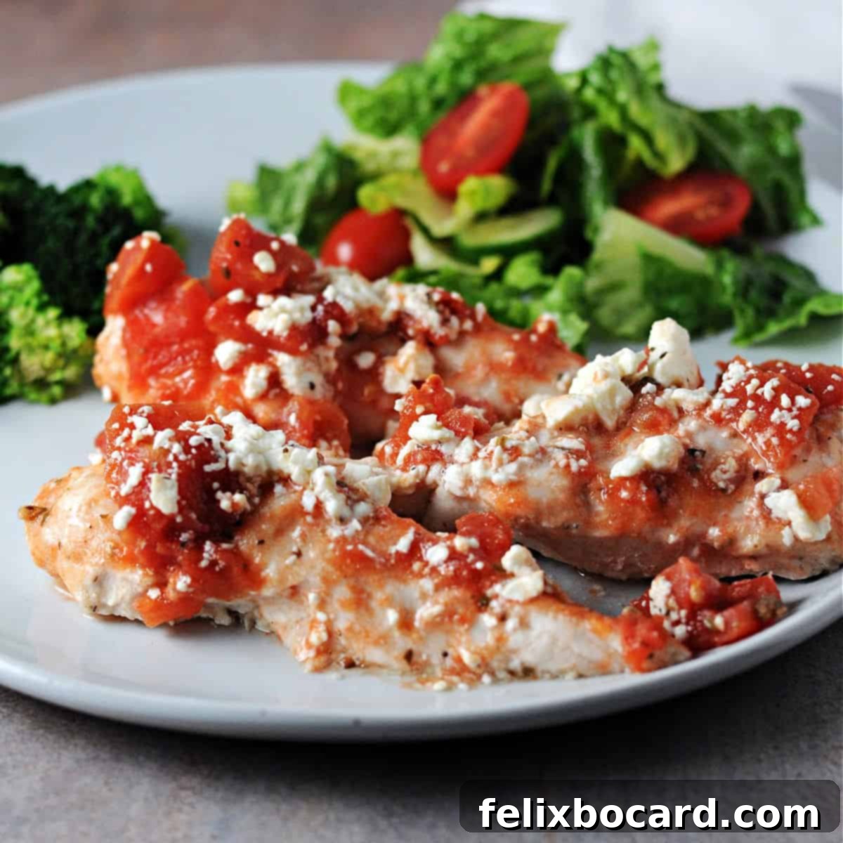 Healthy baked feta chicken tenderloins on a plate with salad, a perfect light meal.