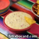 A small red bowl filled with a smooth, golden queso dip, ready to be served, perfect for dipping.