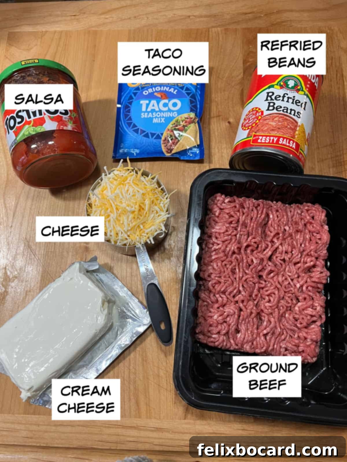 Ingredients: salsa, taco seasoning, refried beans, ground beef, cream cheese, and shredded cheese laid out on a table.