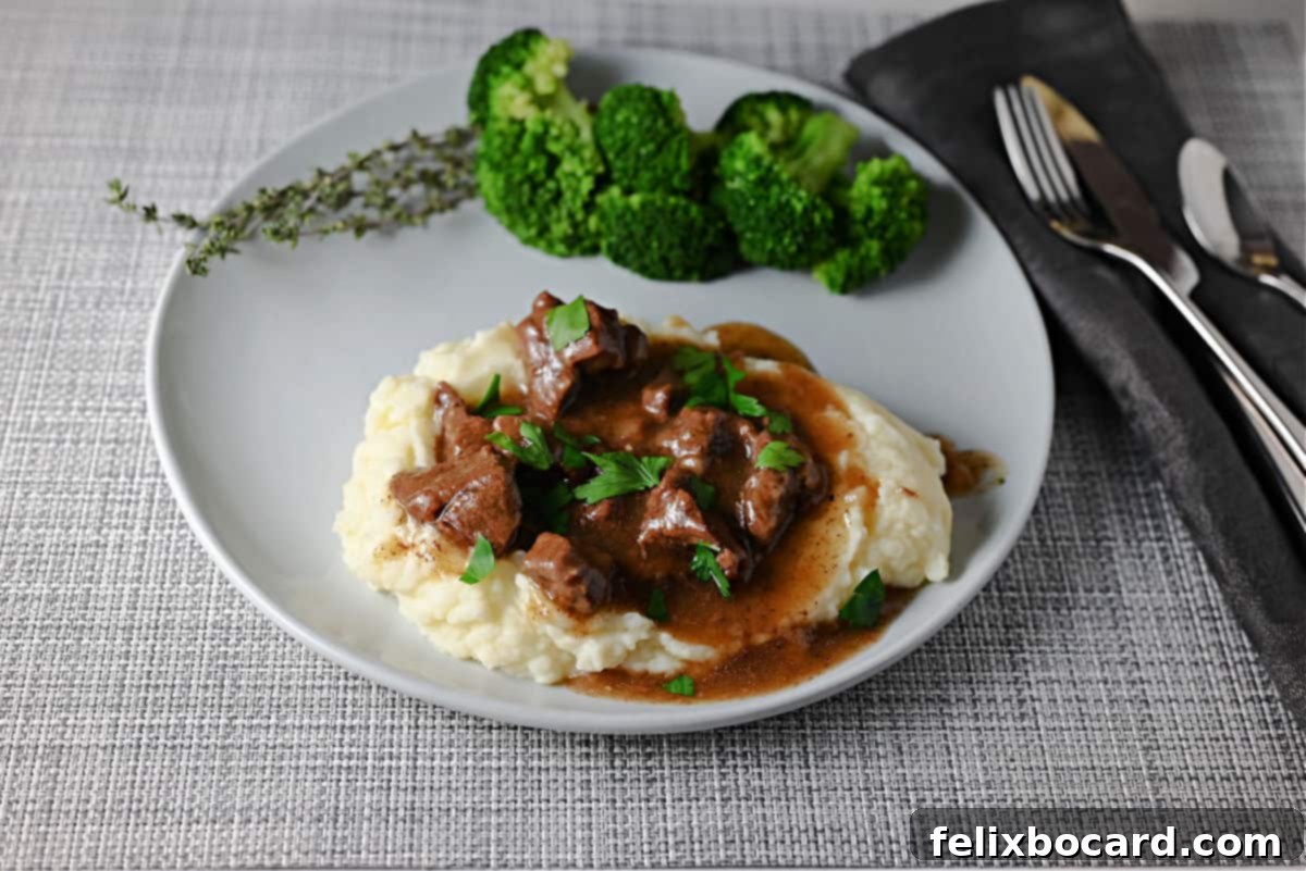 Instant Pot Beef Tips and gravy served on creamy mashed potatoes, garnished with fresh parsley.