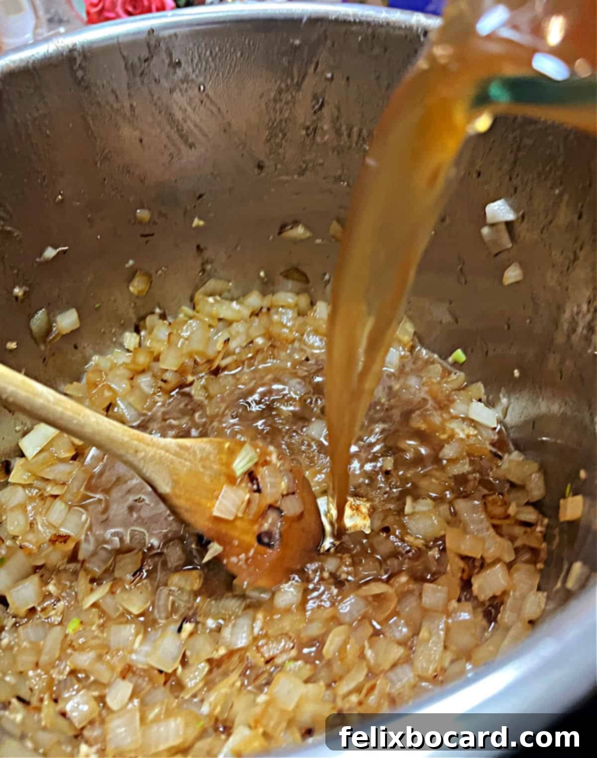 Beef broth being poured into the Instant Pot with sautéed onions and garlic, preparing for deglazing.