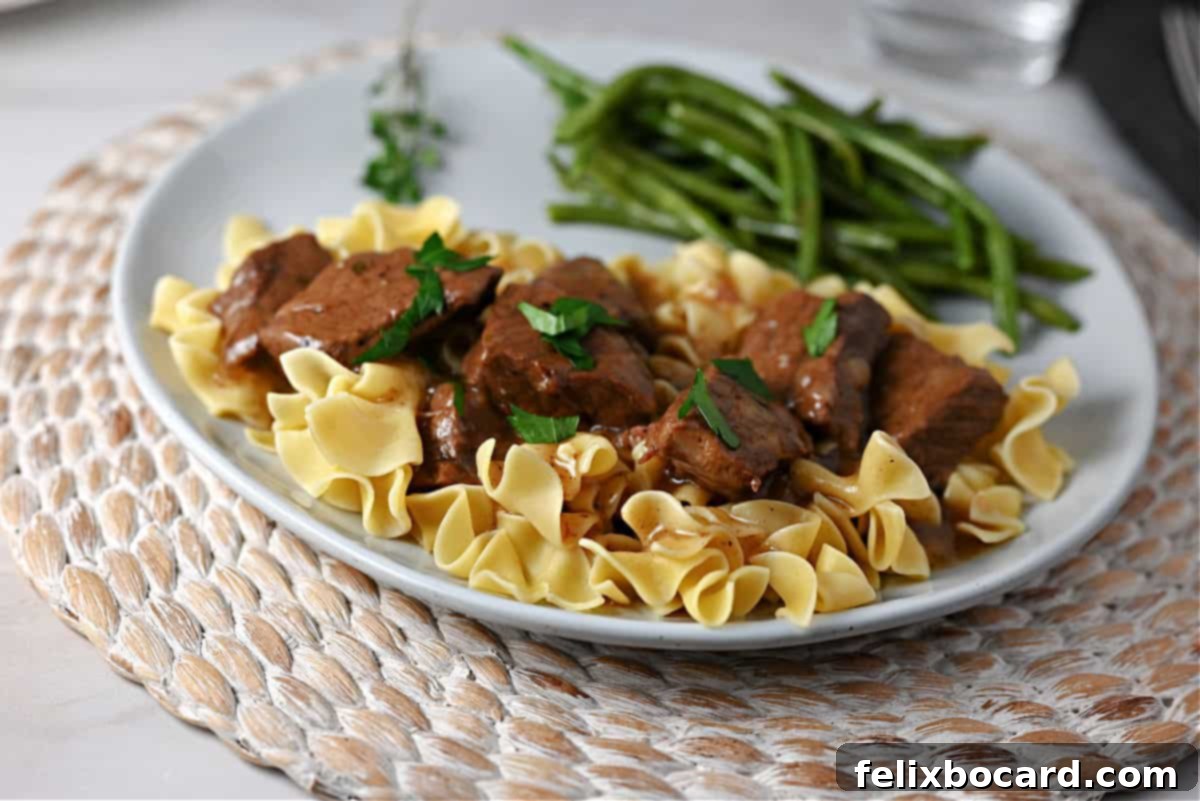 Instant Pot Beef Tips and gravy generously served over a bed of egg noodles, showcasing the rich sauce.