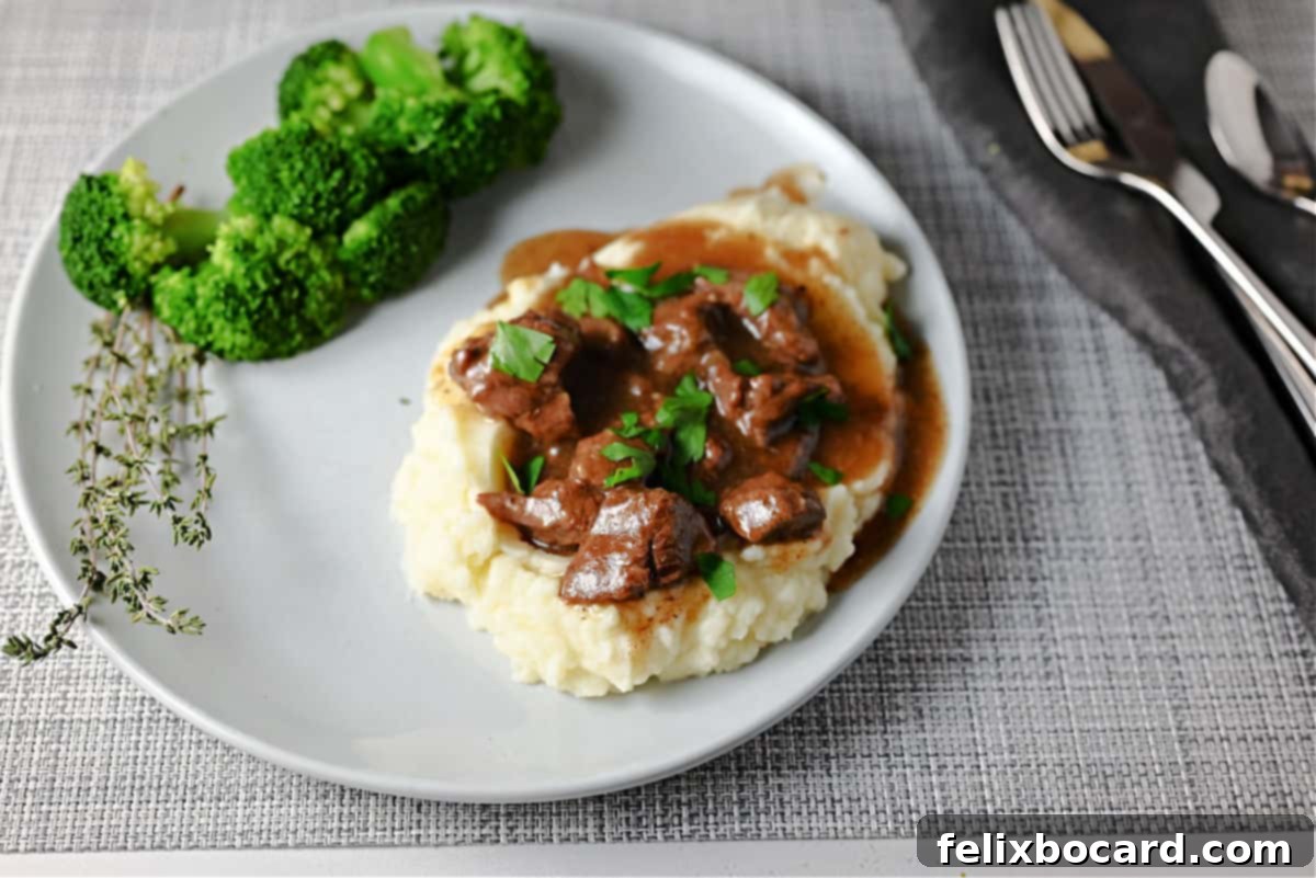Instant Pot Beef Tips and gravy served over mashed potatoes with a side of fresh broccoli, ready for a comforting meal.