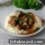 Instant Pot Beef Tips and gravy served on mashed potatoes with some broccoli.