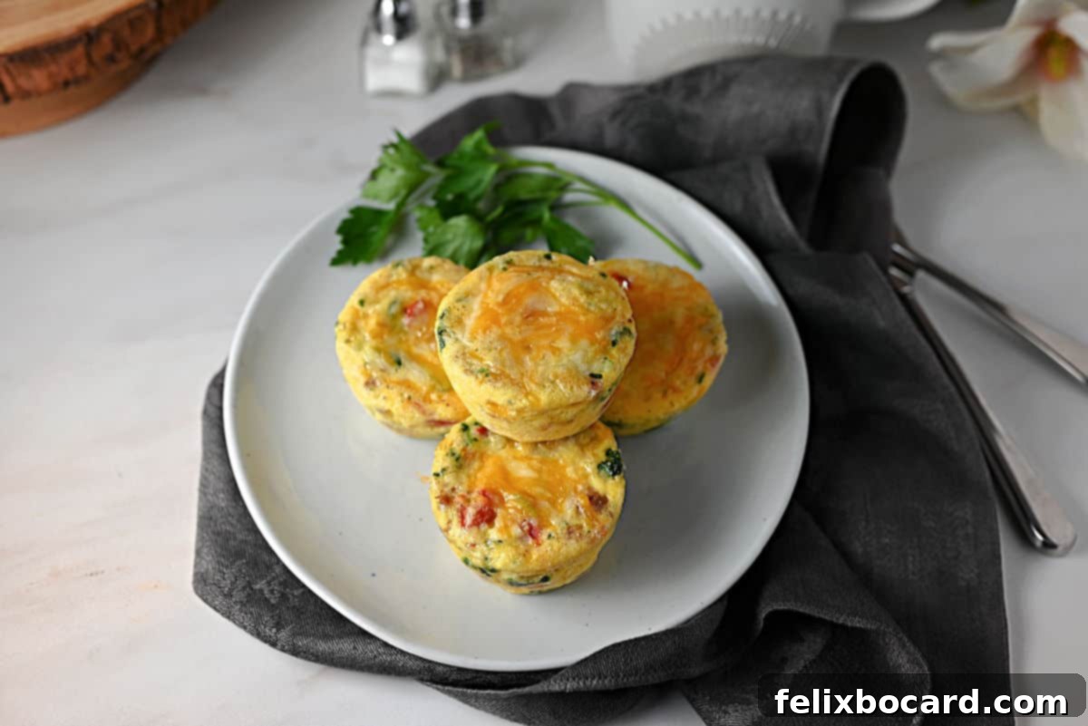 Savory Sausage and Egg Cups 9 A small white plate with several cooked sausage, cheese, and egg bites, ready to be eaten.