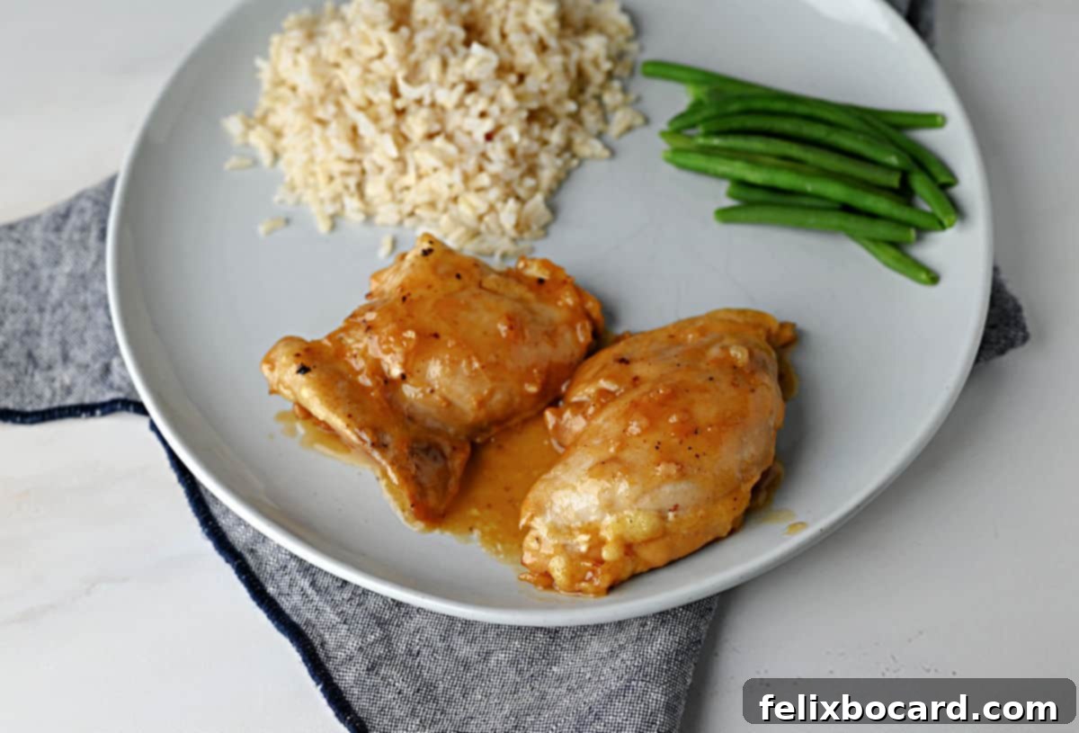 2 pieces of apricot chicken thighs on a plate with rice and green beans.