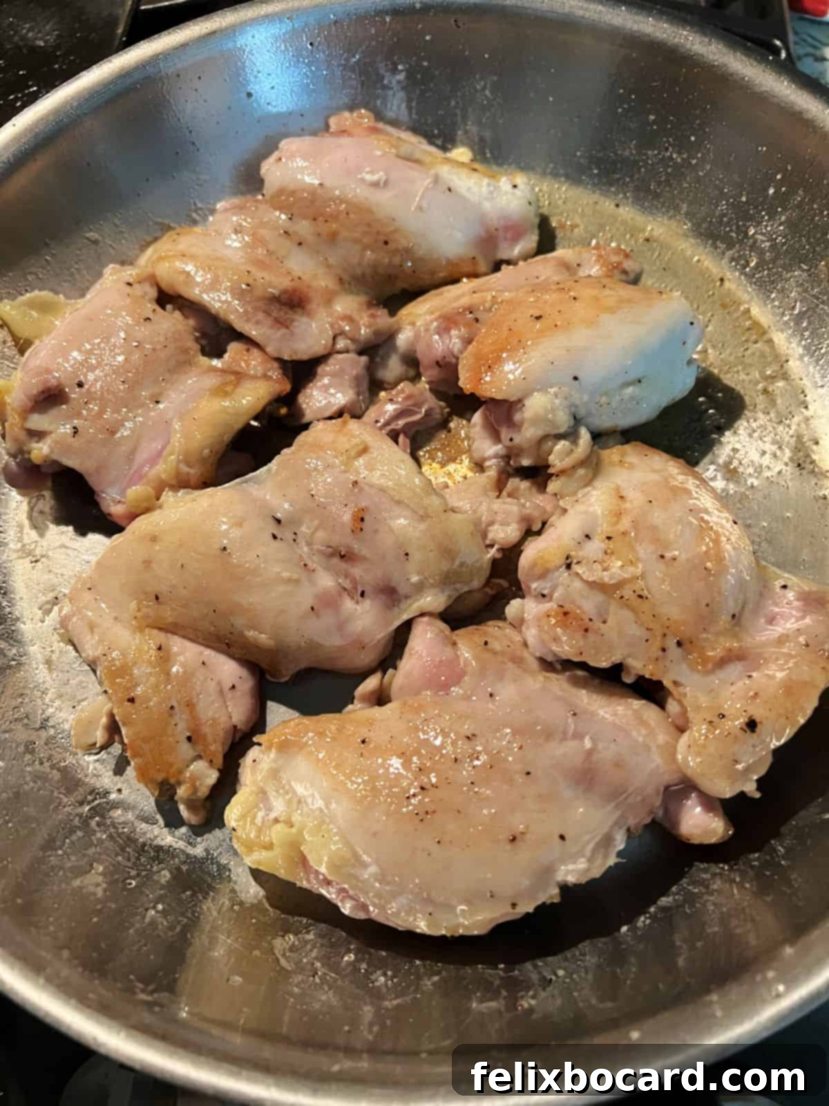 Chicken thighs cooking in a skillet.
