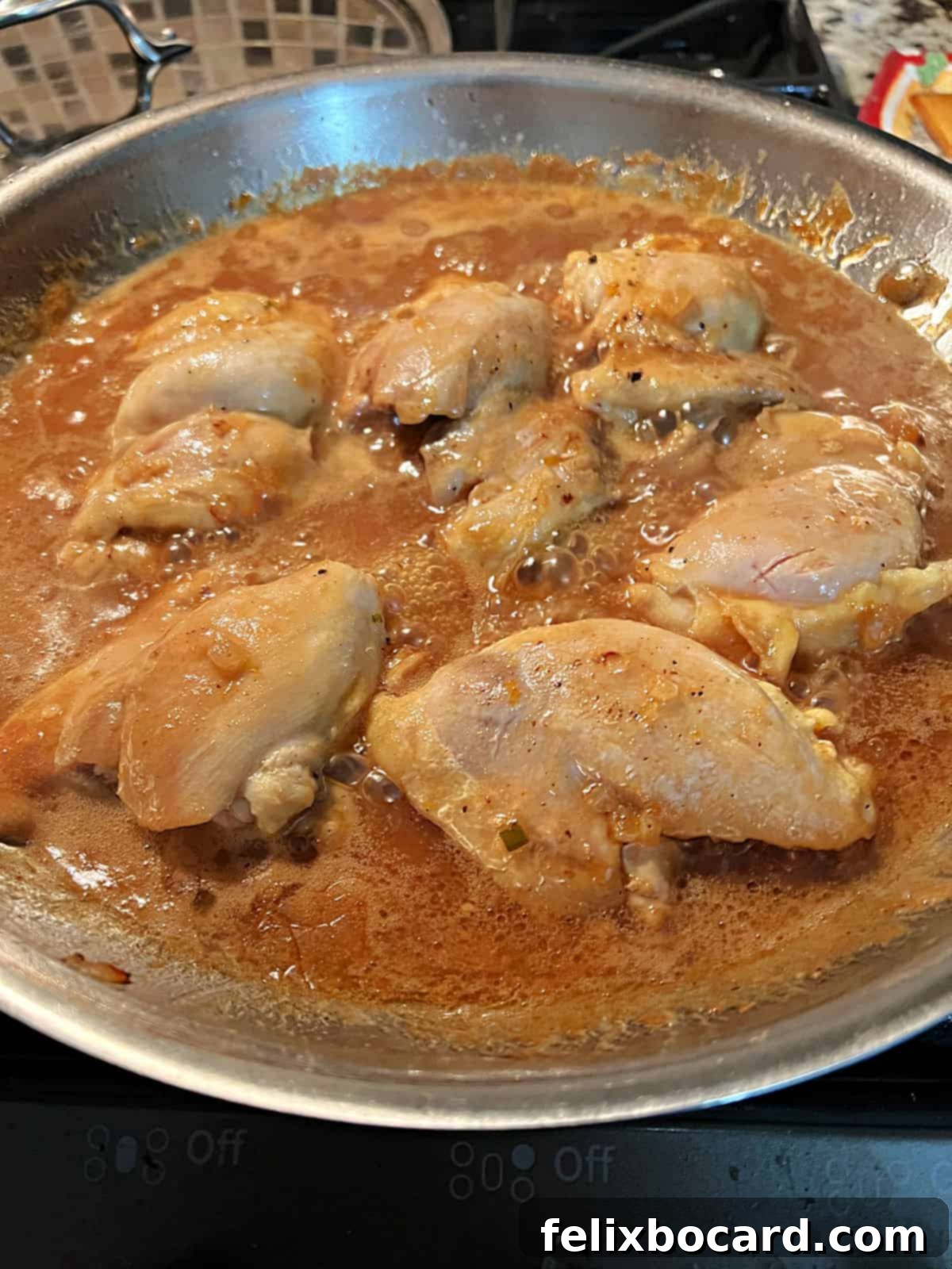 Chicken and sauce cooking together in the skillet.