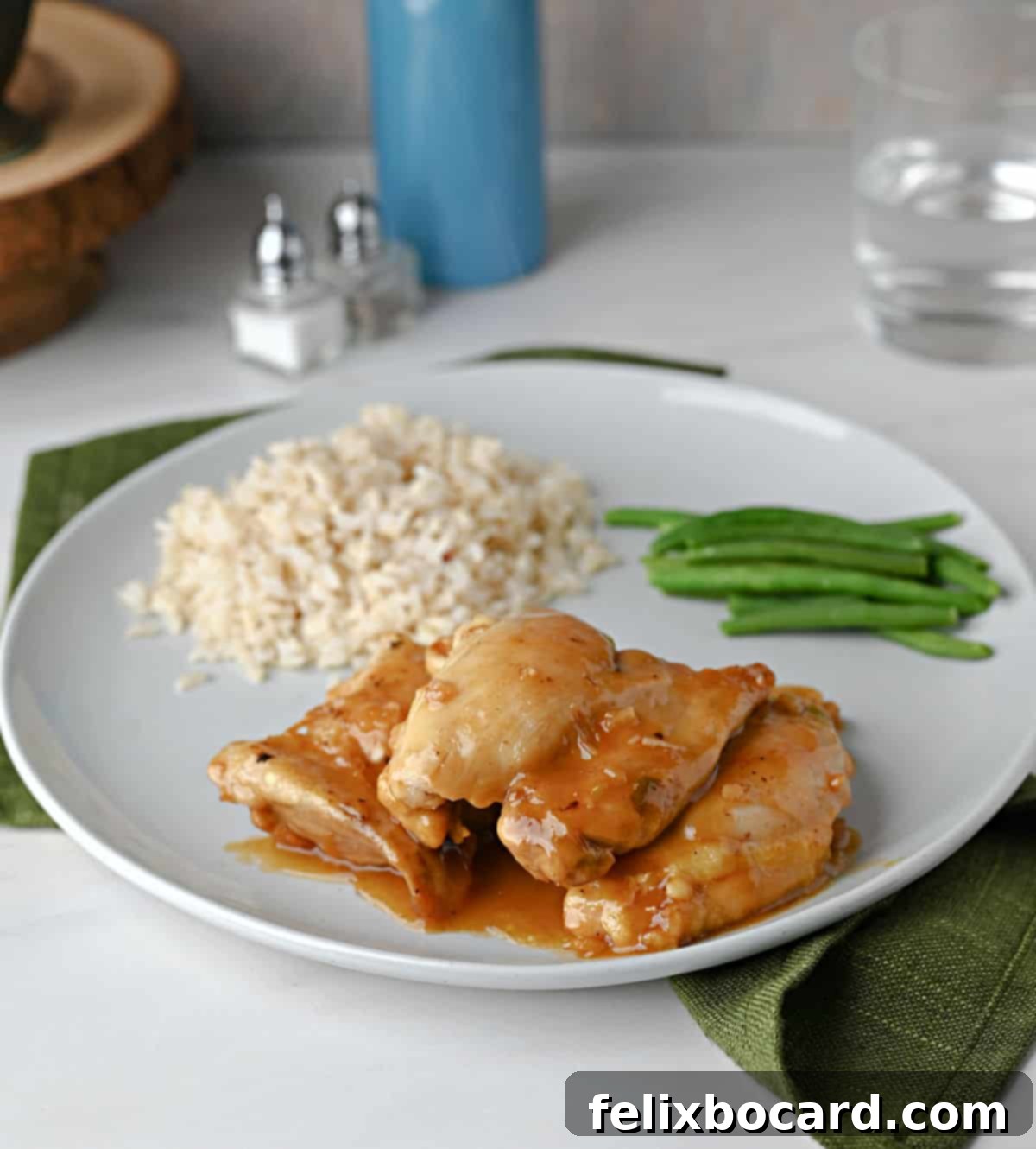 A plate with apricot chicken, brown rice, and green beans ready to eat.