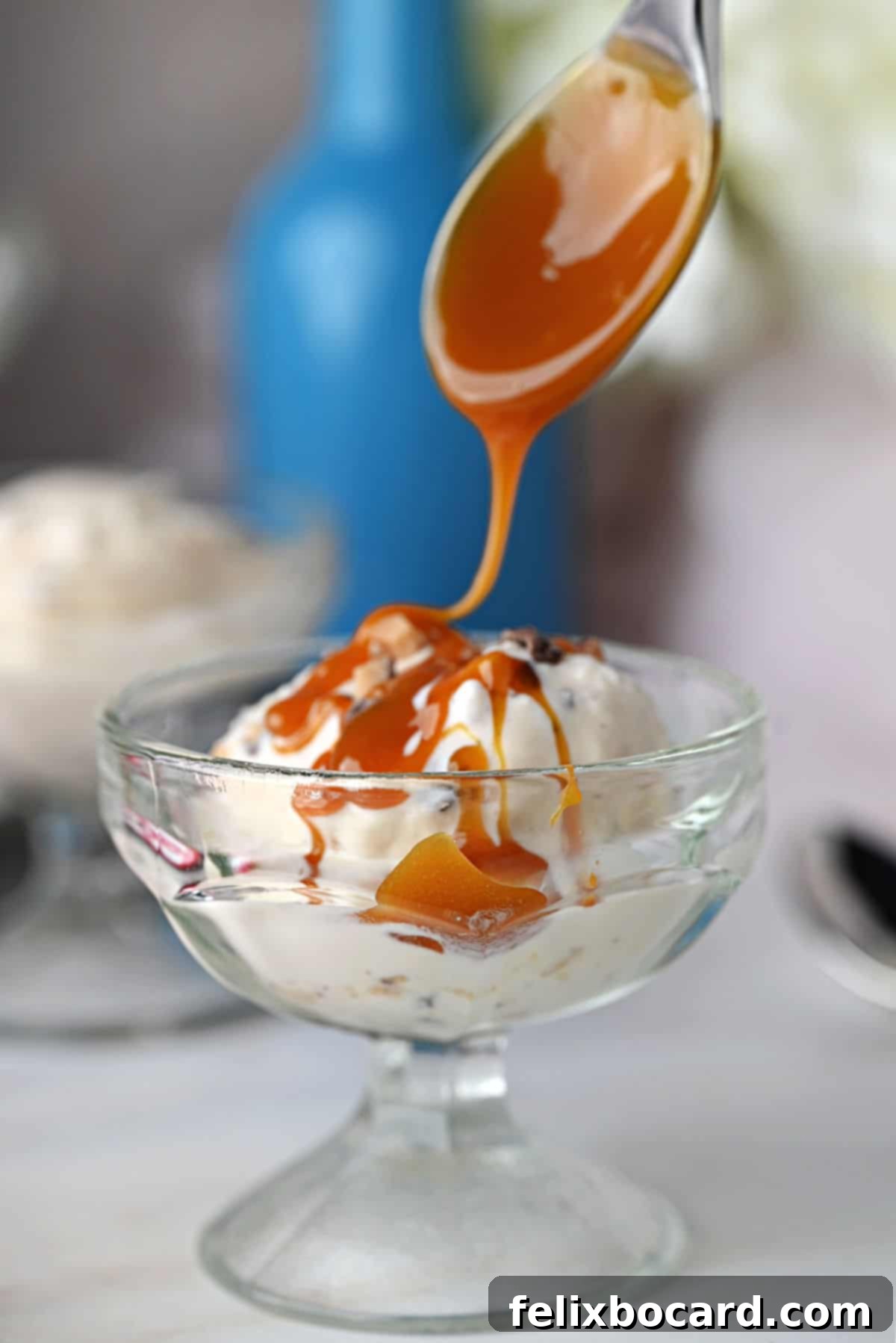 Rich caramel sauce being drizzled generously over a scoop of homemade Toffee Ice Cream in a elegant dessert glass.