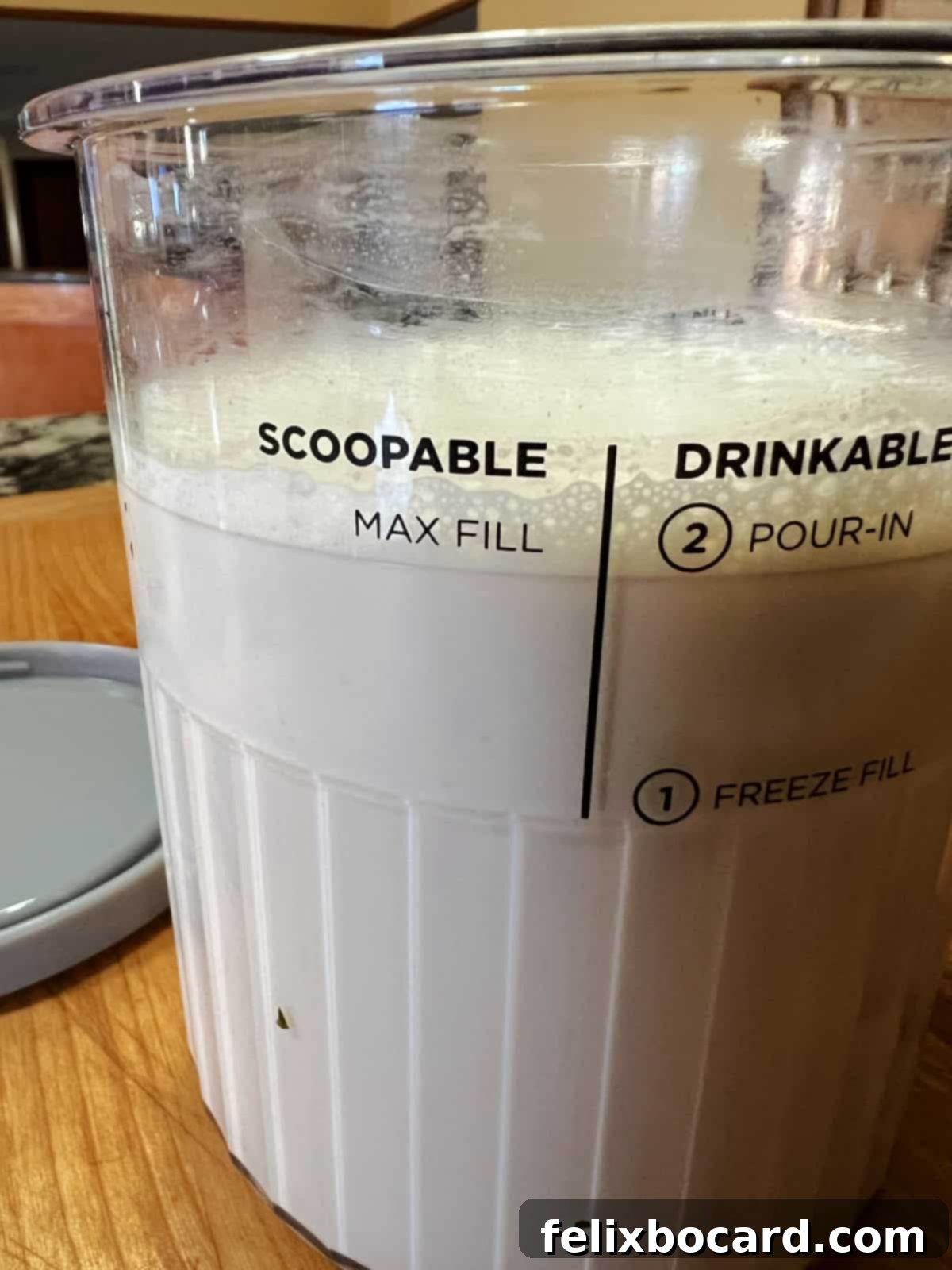 A Ninja Creami Deluxe pint, filled with the liquid ice cream base up to the maximum fill line, ready for freezing.