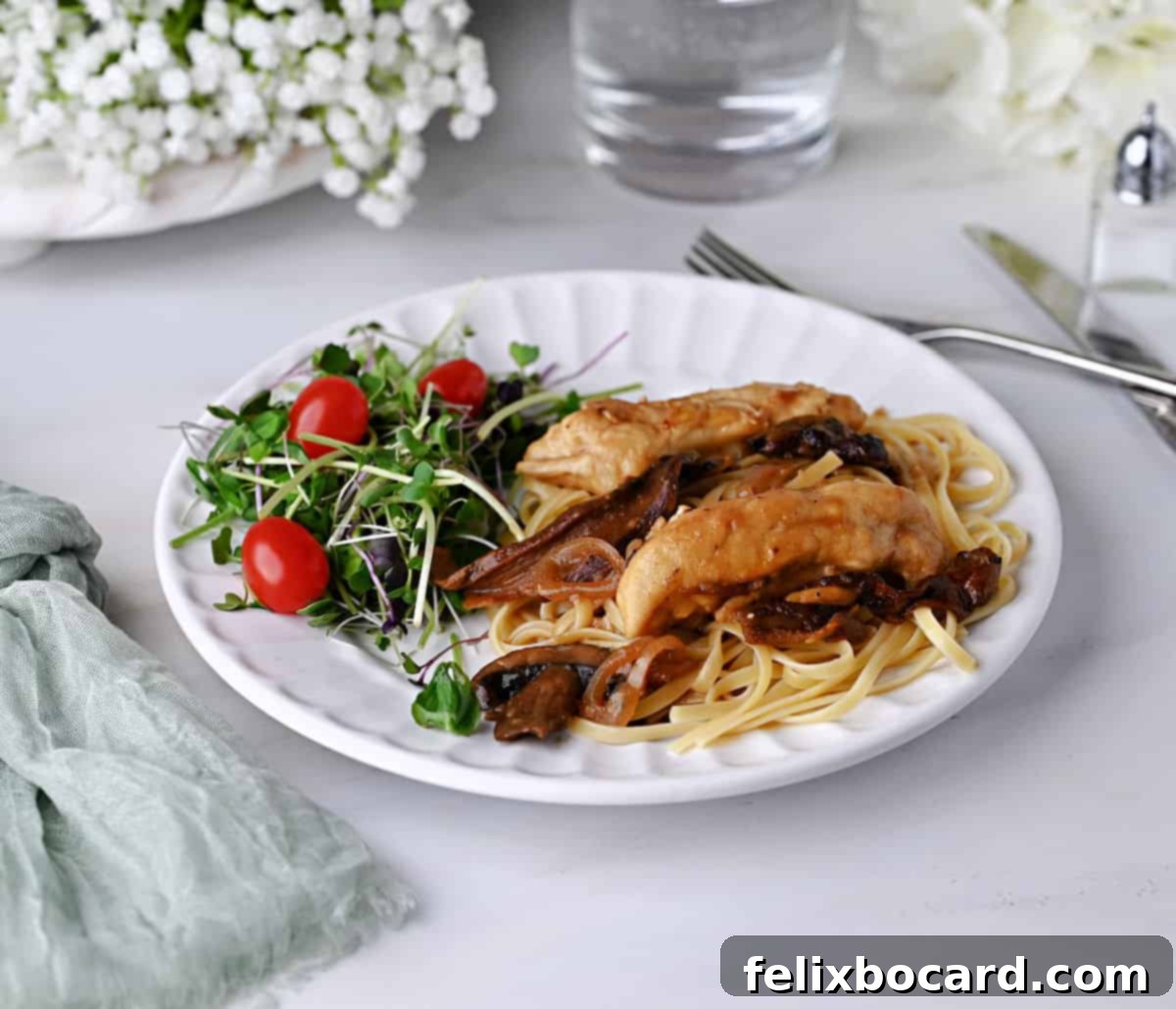 Delicious Chicken Marsala on fettuccine noodles with a fresh side salad, ready to be enjoyed.