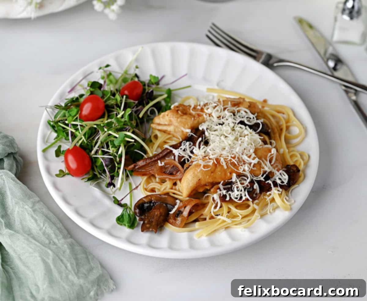 Chicken Marsala on noodles, generously dusted with freshly grated Parmesan cheese.
