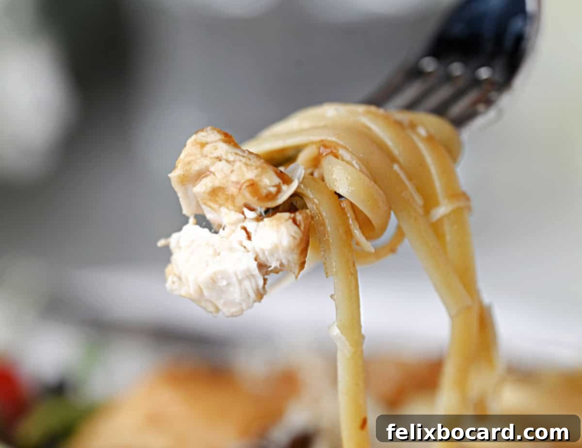 A forkful of fettuccine noodles and chicken Marsala, ready to eat.