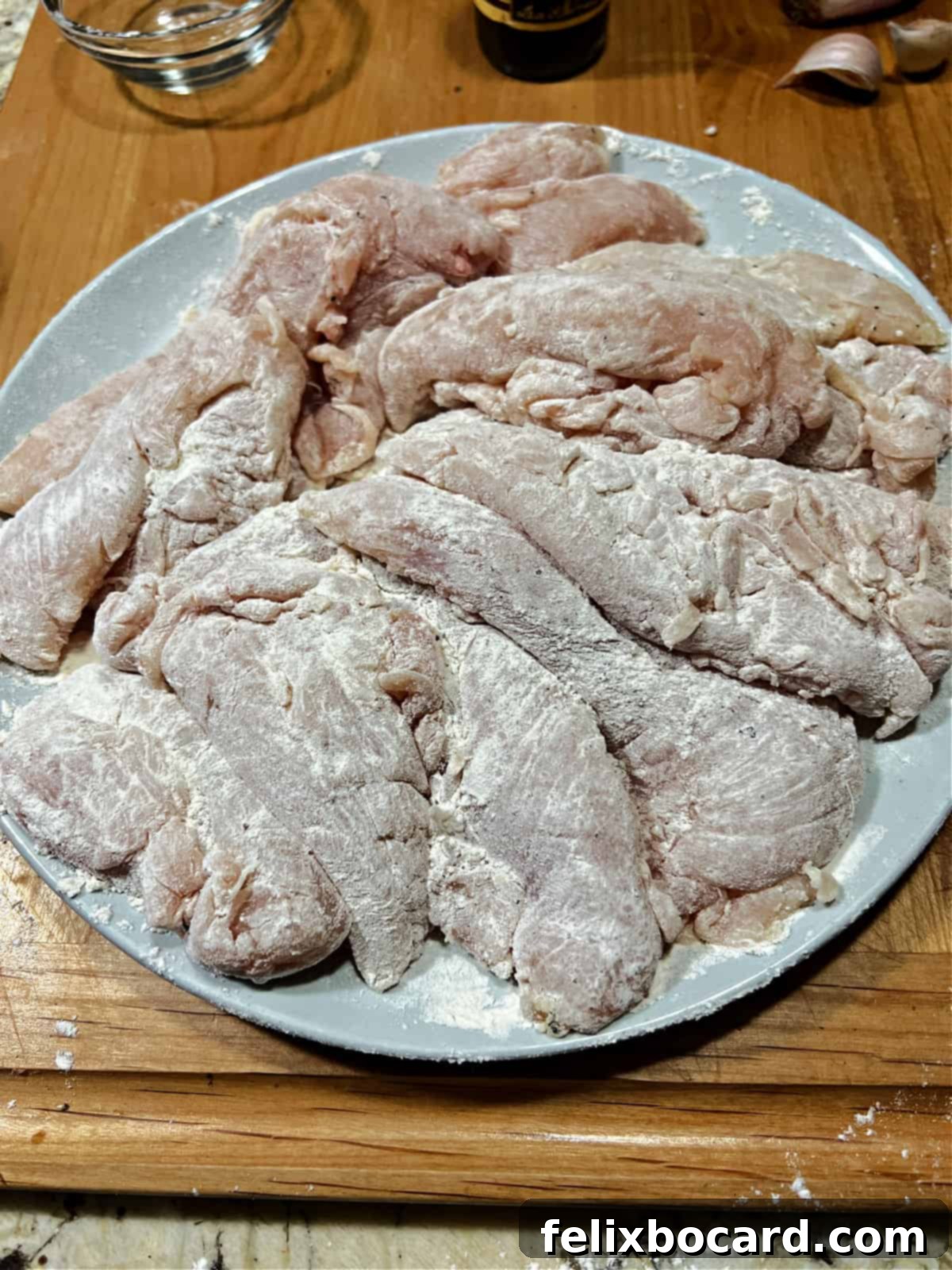 Chicken tenders on a plate, lightly dusted with flour and seasoned.