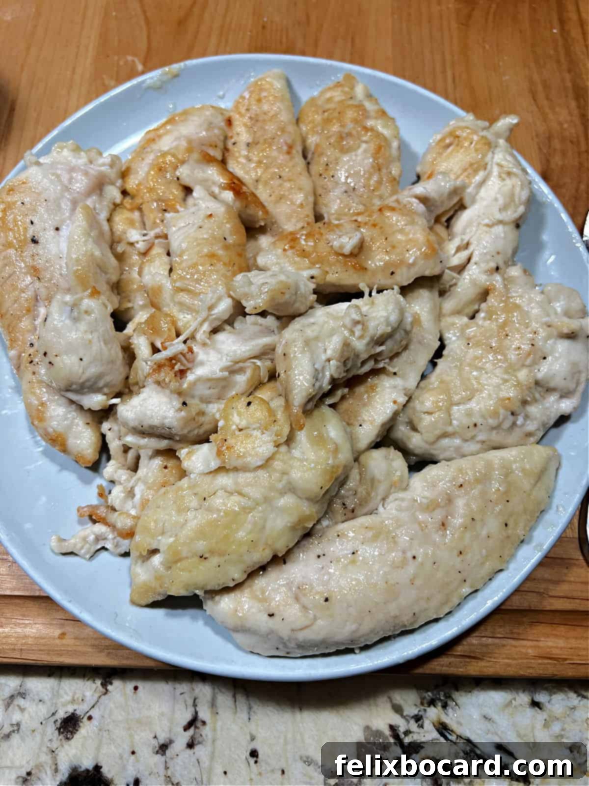 Perfectly cooked golden-brown chicken tenders resting on a plate after searing.