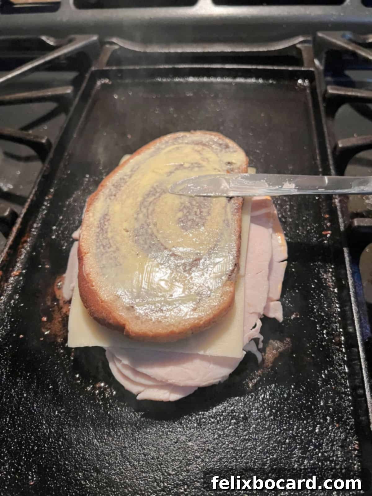 Golden Grilled Turkey Reuben 11 Buttering the other side of the sandwich while it is cooking on the grill.