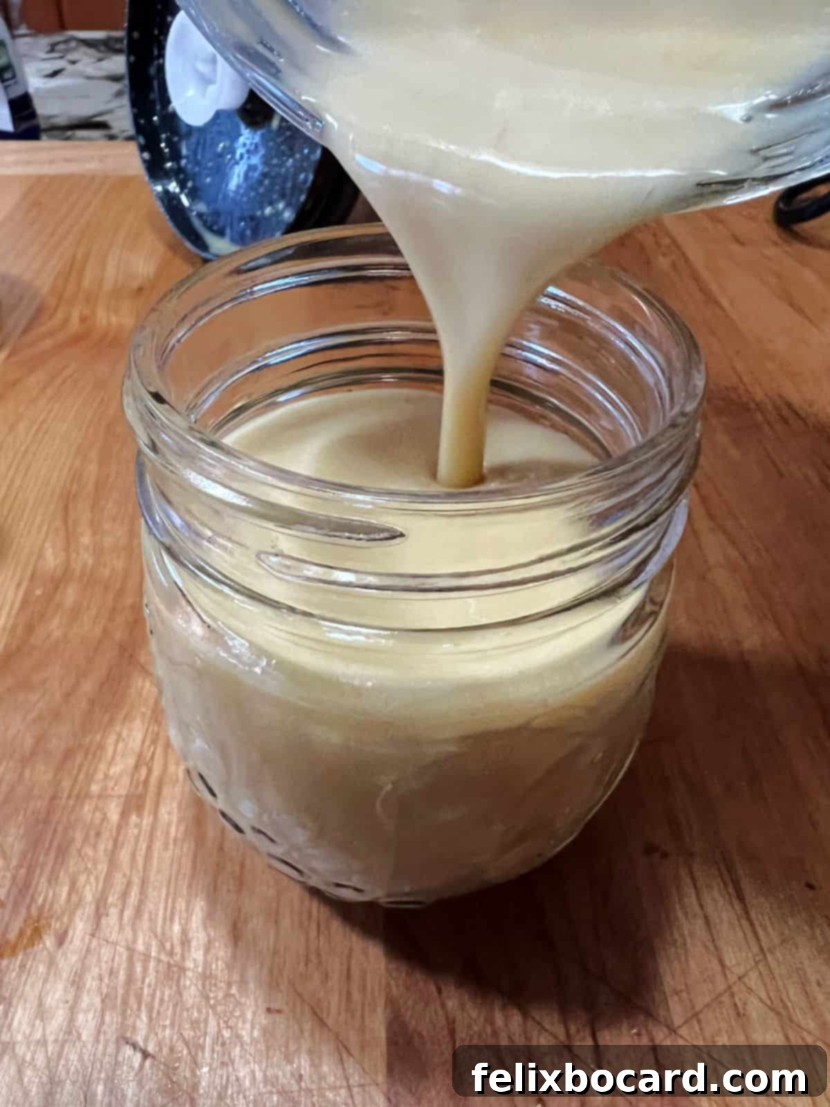 Pouring freshly blended honey lime dressing from a blender into a glass jar for convenient storage in the refrigerator.