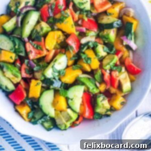A vibrant mango cucumber salad with creamy avocado and fresh mint, presented beautifully for a summer gathering.
