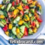 A vibrant mango cucumber salad, generously mixed with creamy avocado and garnished with fresh mint, presented as an enticing feature dish.