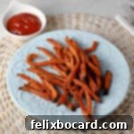 A plate brimming with perfectly cooked sweet potato fries, accompanied by a small ramekin of ketchup for dipping, offering a tempting and delicious snack or side.