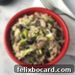 A small red bowl filled with creamy, rich mushroom risotto, showcasing its appetizing texture and garnish.